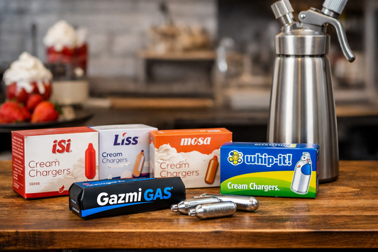 Cream charger brands comparison featuring Gazmi Gas nitrous oxide chargers with iSi, Liss, Mosa and Whip-It beside a stainless steel whipped cream dispenser.
